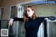 A woman in a black dress leaning against a refrigerator.