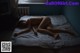 A naked woman laying on a bed in a dark room.