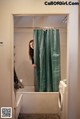 A woman standing in a bathroom next to a bathtub.