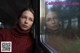 A woman in a red sweater looking out of a train window.