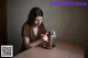 A woman sitting at a table with a grater in front of her.