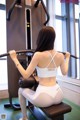 A woman in a white sports bra top and leggings working out in a gym.