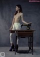 A naked woman standing next to a sewing machine.