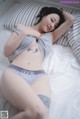 A woman laying on a bed in a gray shirt and panties.