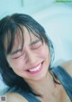 A smiling woman taking a bath in a bathtub.