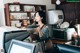 A woman is making a cup of coffee at a coffee shop.