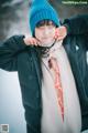 A woman wearing a blue hat and scarf in the snow.