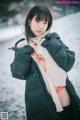 A woman in a black jacket and scarf standing in the snow.