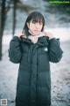 A woman wearing a black coat standing in the snow.