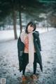 A woman standing in the snow wearing a scarf.