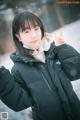 A woman in a black jacket standing in the snow.