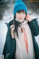 A woman wearing a blue hat and scarf in the snow.