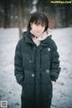 A woman standing in the snow wearing a black jacket.