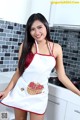 A woman in an apron posing in a kitchen.