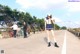 A woman wearing a face mask standing on the side of a road.