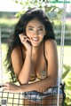 A woman in a leopard print bikini sitting on a swing.