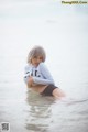 A woman sitting in the water with her arms crossed.