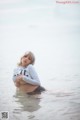 A woman sitting in the water with her arms crossed.