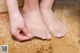 A woman is putting on a pair of barefoot sandals.