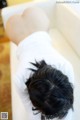 A woman laying in a bathtub with her back to the camera.