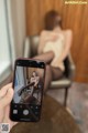 A person taking a picture of a woman sitting on a chair.