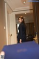 A woman in a business suit standing in a hotel room.