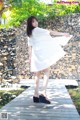 A woman in a white dress is standing on a wooden dock.