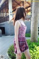 A woman in a red and white dress standing on a wooden walkway.