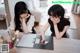 Two women sitting at a table looking at a cell phone.