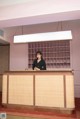 A woman standing behind a reception desk in a hotel.