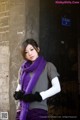 A woman wearing a purple scarf and black gloves.