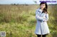 A woman standing in a field with her arms crossed.