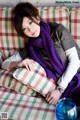 A woman laying on a couch wearing a purple scarf.