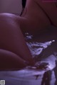 A nude woman laying in the water with her back to the camera.