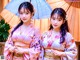 Two young women in kimonos holding umbrellas in the rain.