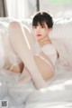 A woman in a white lingerie sitting on a bed.