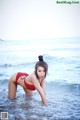 A woman in a red bikini standing in the ocean.