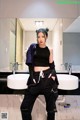 A woman standing in front of a bathroom sink.