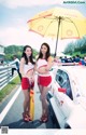 A couple of women standing next to each other holding an umbrella.