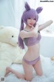 A woman in a purple lingerie posing with a teddy bear.