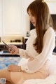 A woman sitting on a bed looking at her phone.