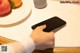 A person using a cell phone on a table with a plate of fruit.