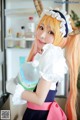 A woman in a maid outfit holding a bottle of water.