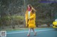 A woman in a yellow coat is walking down the street.