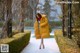 A woman in a yellow coat is walking down a sidewalk.