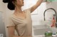 A woman standing in front of a sink in a kitchen.