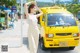 A woman standing in front of a yellow taxi.