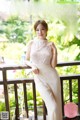 A woman in a white dress standing on a balcony.