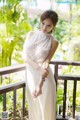 A woman in a white dress standing on a balcony.