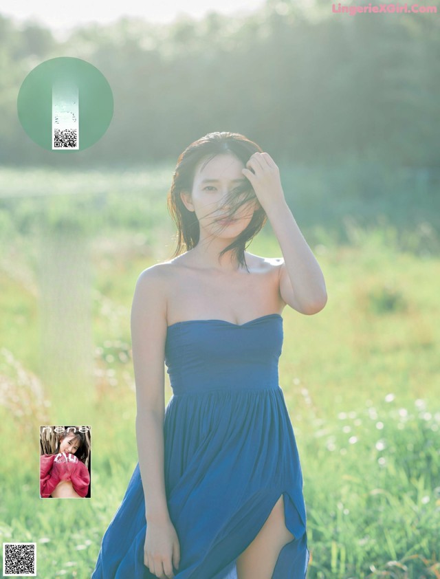 A woman in a blue dress standing in a field.